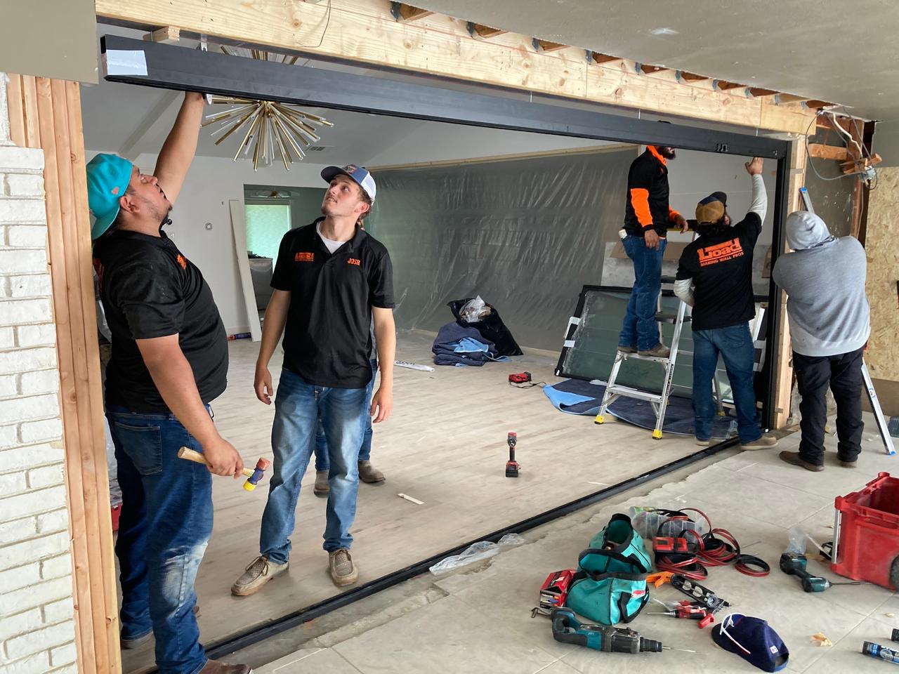 Wall to door conversion — crew installing structural support beam and glass sliding doors Texas